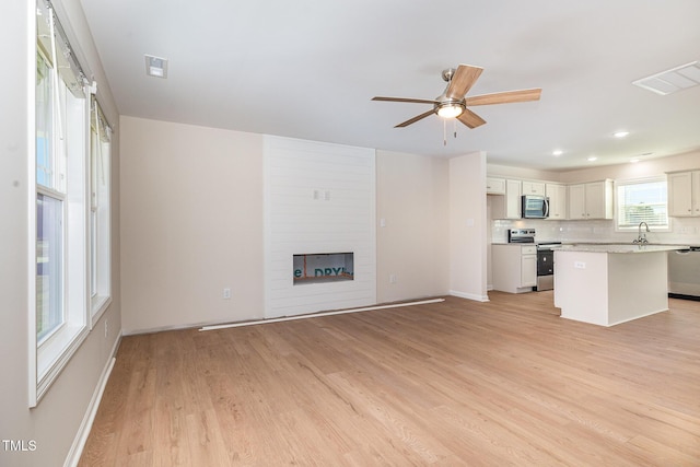 300 Tuscany Cir, Princeton, NC 27569 - unfurnished living room featuring a fireplace, visible vents, light wood-type flooring, and ceiling fan