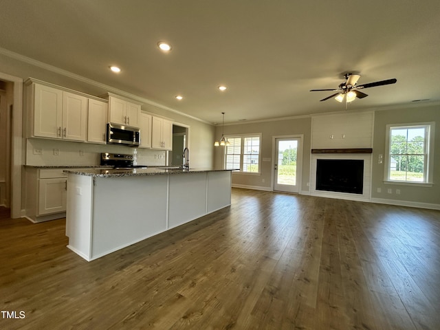 3912 Origin Dr, Bailey, NC 27807 - kitchen with appliances with stainless steel finishes, ornamental molding, white cabinets, a center island with sink, and dark wood-style flooring