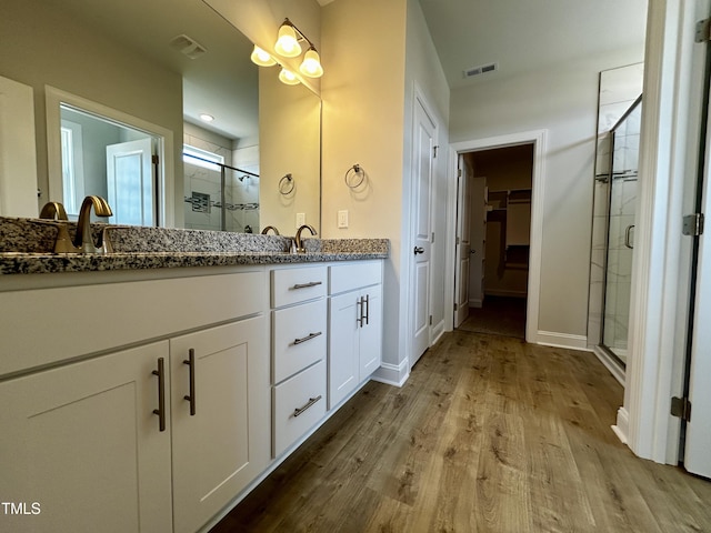 3912 Origin Dr, Bailey, NC 27807 - full bath with double vanity, a shower stall, wood finished floors, a walk in closet, and baseboards