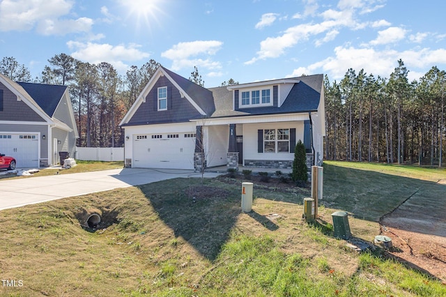 view of front of property with an attached garage, stone siding, fence, concrete driveway, and a front lawn