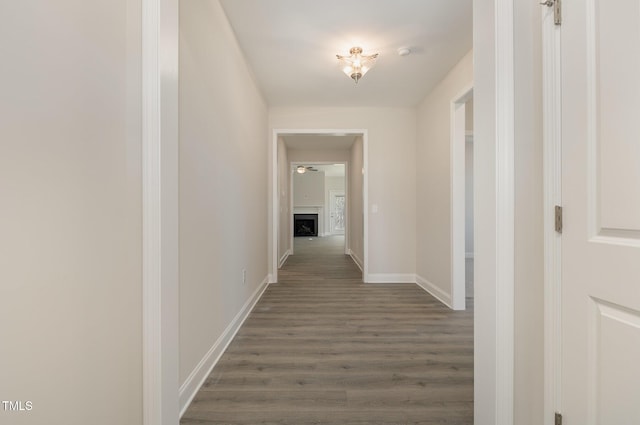 corridor featuring dark wood-style flooring and baseboards