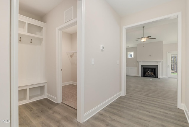 mudroom with visible vents, baseboards, ceiling fan, a fireplace, and wood finished floors