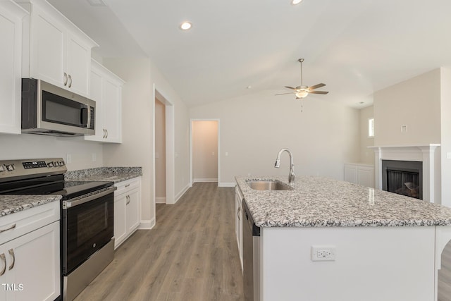 kitchen with white cabinetry, a ceiling fan, appliances with stainless steel finishes, a sink, and lofted ceiling