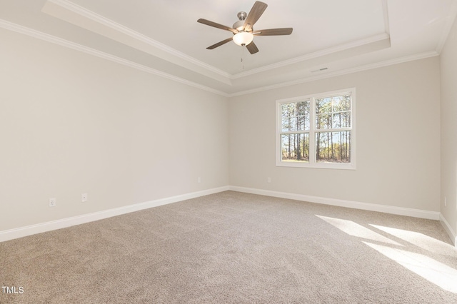 spare room featuring baseboards, a raised ceiling, crown molding, ceiling fan, and carpet