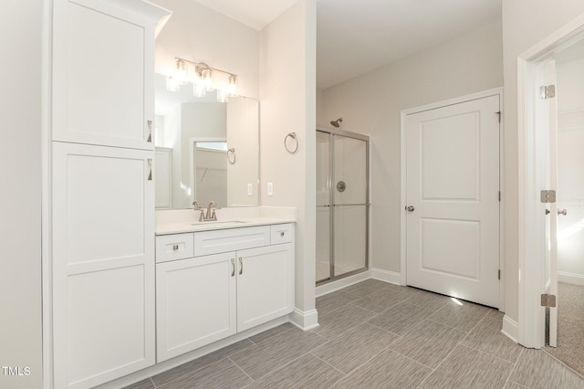 bathroom featuring a stall shower, vanity, and baseboards