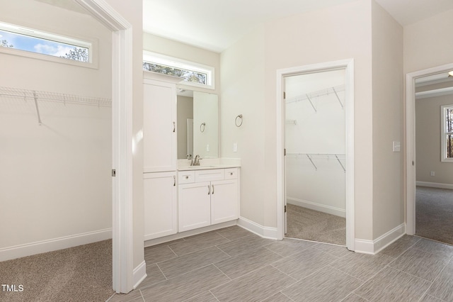 full bathroom featuring vanity, baseboards, and a spacious closet