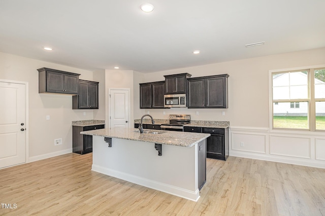 18 Bonnybrook Ct, Selma, NC 27576 - kitchen with stainless steel appliances, light wood-style floors, light stone counters, a kitchen island with sink, and recessed lighting