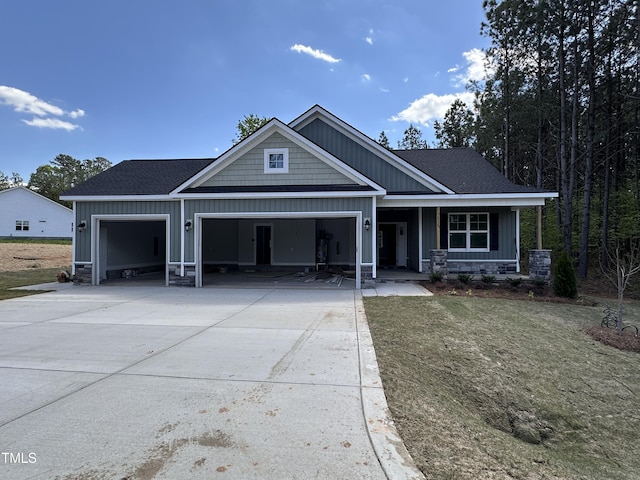craftsman-style home featuring stone siding, covered porch, concrete driveway, a garage, and board and batten siding