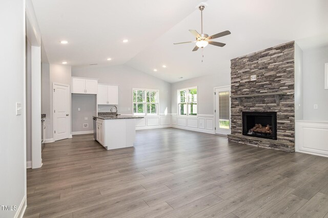 98 Laramie Ln, Selma, NC 27576 - unfurnished living room with ceiling fan, vaulted ceiling, wainscoting, wood finished floors, and a stone fireplace