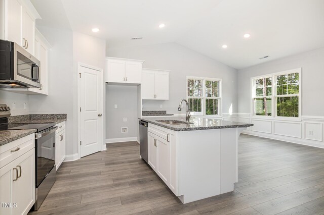 98 Laramie Ln, Selma, NC 27576 - kitchen with appliances with stainless steel finishes, dark stone counters, wood finished floors, vaulted ceiling, and wainscoting