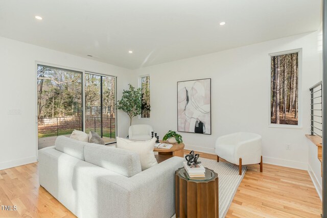 living room featuring baseboards, light wood-style flooring, and recessed lighting