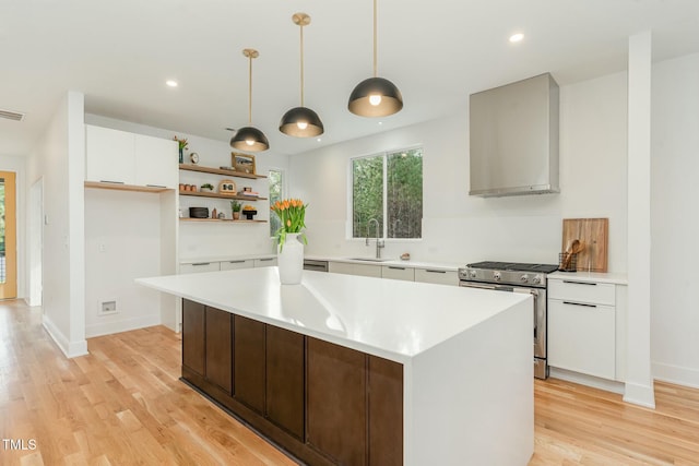 kitchen featuring light countertops, stainless steel gas stove, a sink, open shelves, and white cabinetry