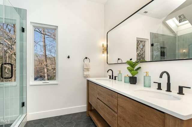 full bath featuring a shower stall, double vanity, a skylight, and a sink