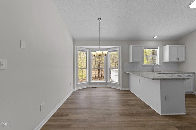 5408 Rivercrest Dr, Youngsville, NC 27596 - kitchen with white cabinetry, a notable chandelier, a sink, and dark wood-type flooring