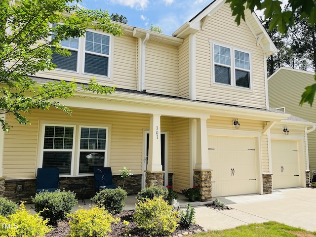 303 Fortress Dr, Morrisville, NC 27560 - craftsman house with an attached garage, a porch, driveway, and stone siding
