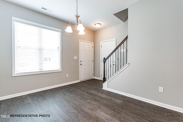 foyer entrance with a chandelier, dark wood-style floors, baseboards, and stairs