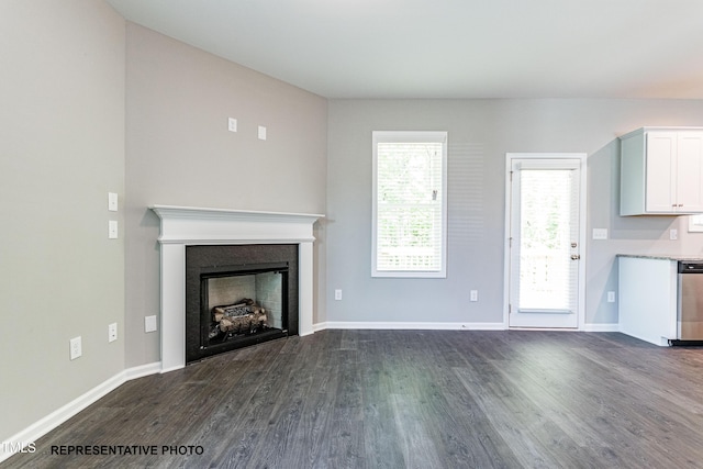 unfurnished living room with dark wood finished floors, a fireplace, and baseboards