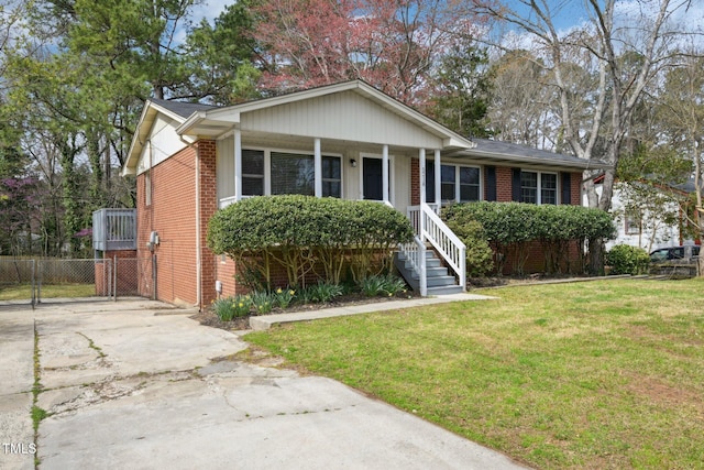 view of front of home featuring a front yard, a porch, fence, concrete driveway, and brick siding
