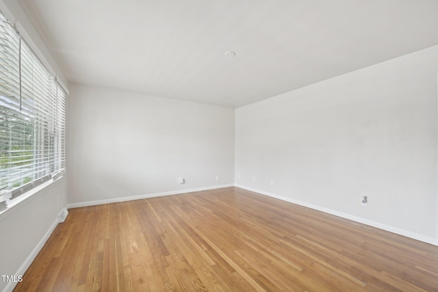 spare room featuring baseboards and light wood-style floors
