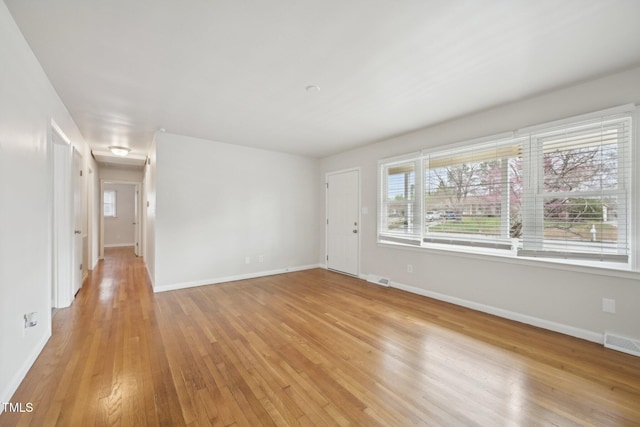 unfurnished room featuring visible vents, baseboards, and light wood-style floors