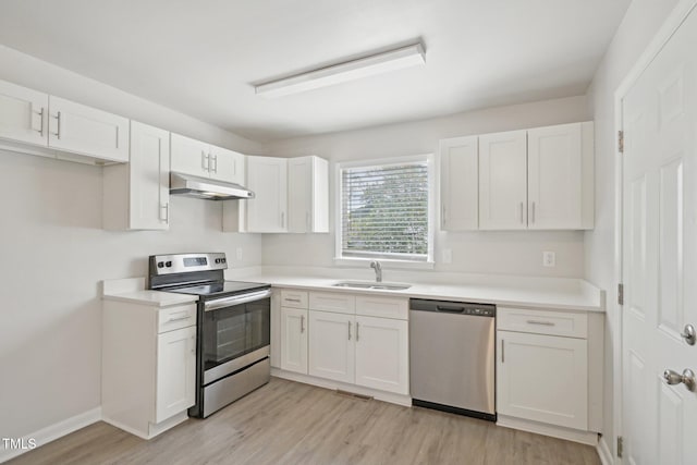 kitchen with under cabinet range hood, white cabinetry, a sink, and appliances with stainless steel finishes