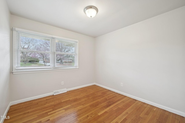 empty room with light wood-type flooring, baseboards, and visible vents