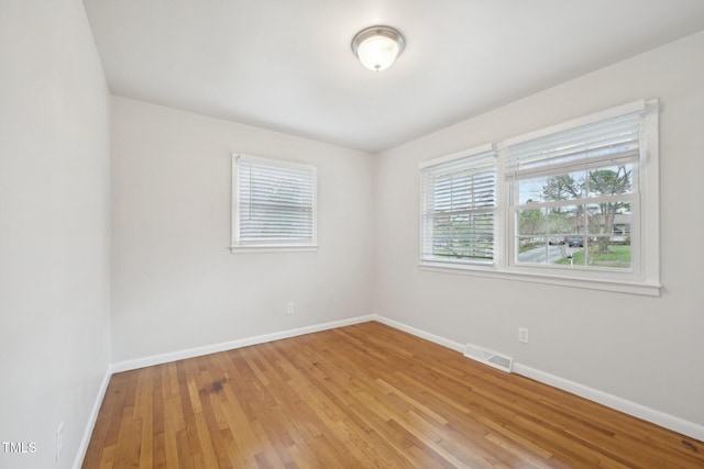 spare room featuring light wood finished floors, baseboards, and visible vents