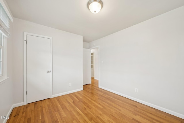 unfurnished bedroom with light wood finished floors, multiple windows, and baseboards