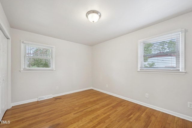 empty room featuring a wealth of natural light, light wood-style floors, and baseboards