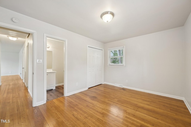unfurnished bedroom with a closet, light wood finished floors, and baseboards