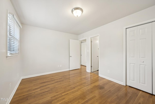 unfurnished bedroom with a closet, baseboards, and wood finished floors