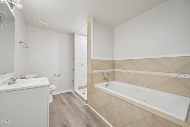 bathroom with visible vents, a bath, toilet, vanity, and wood finished floors