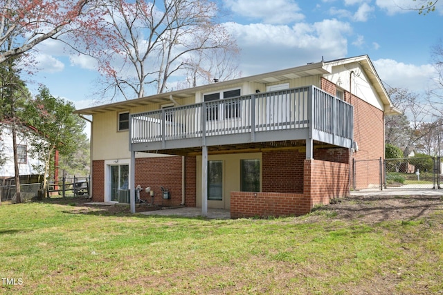 back of house with brick siding, fence, a wooden deck, and a lawn