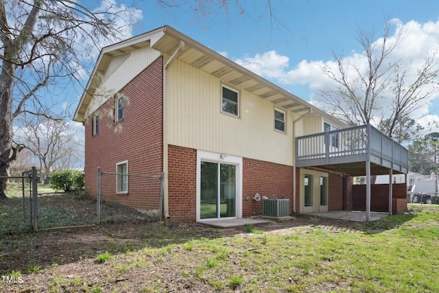 back of property featuring a wooden deck, central air condition unit, a lawn, a patio, and brick siding