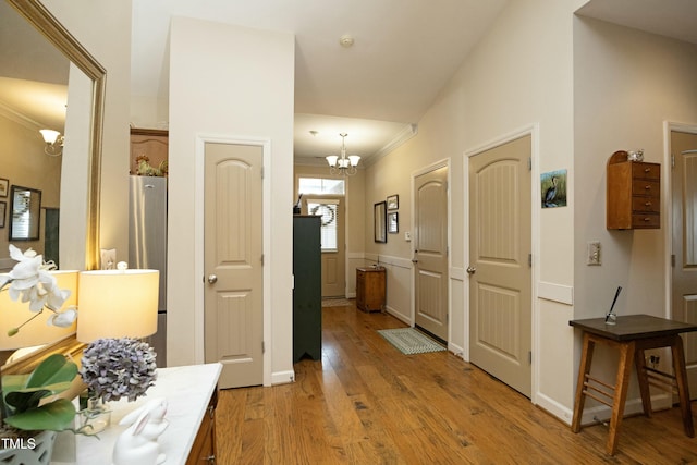 hallway featuring a notable chandelier, light wood-style floors, and ornamental molding