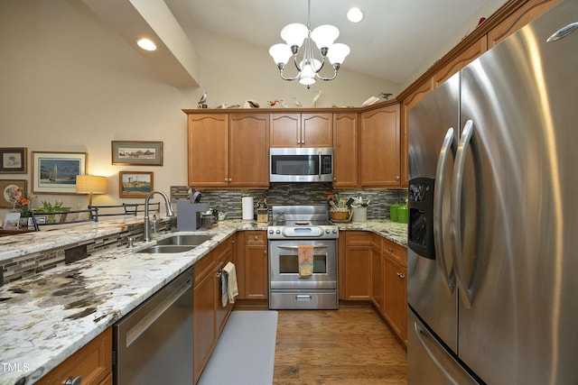 kitchen featuring tasteful backsplash, vaulted ceiling, stainless steel appliances, a sink, and a notable chandelier