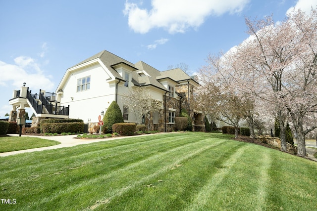 view of side of property with stucco siding, stone siding, and a yard