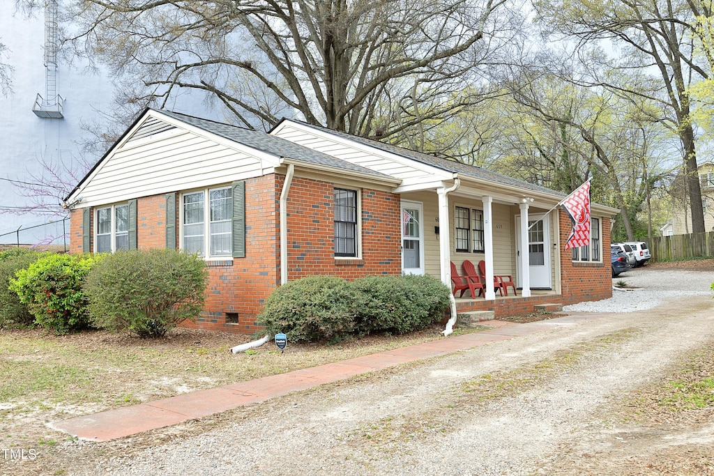bungalow-style home featuring fence, roof with shingles, crawl space, covered porch, and brick siding
