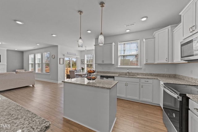 1408 Weavers Trace Dr, Zebulon, NC 27597 - kitchen featuring a sink, a kitchen island, light wood finished floors, open floor plan, and stainless steel appliances