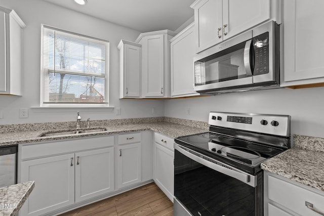 1408 Weavers Trace Dr, Zebulon, NC 27597 - kitchen featuring white cabinetry, a sink, light wood-style floors, light stone counters, and appliances with stainless steel finishes