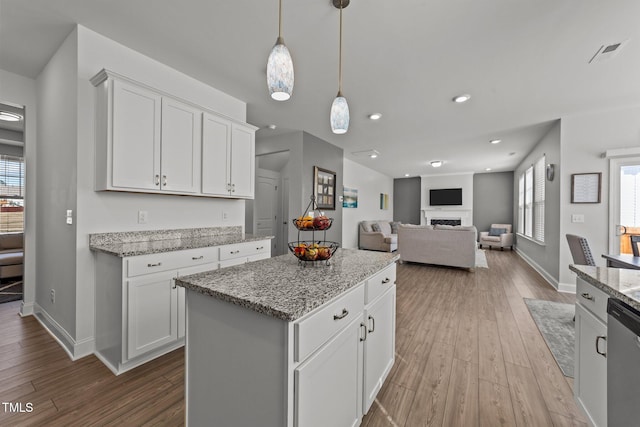 1408 Weavers Trace Dr, Zebulon, NC 27597 - kitchen with dishwasher, white cabinets, light stone countertops, a fireplace, and wood finished floors