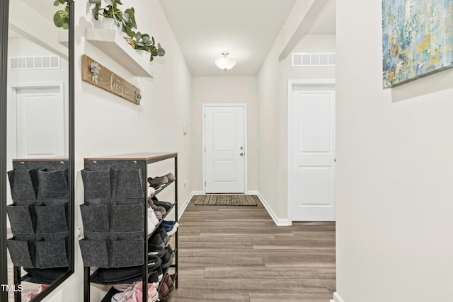 corridor featuring baseboards, visible vents, and wood finished floors
