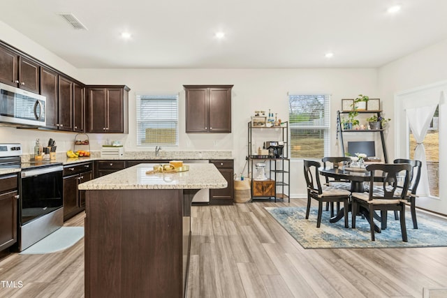kitchen featuring light wood finished floors, visible vents, dark brown cabinetry, and stainless steel appliances