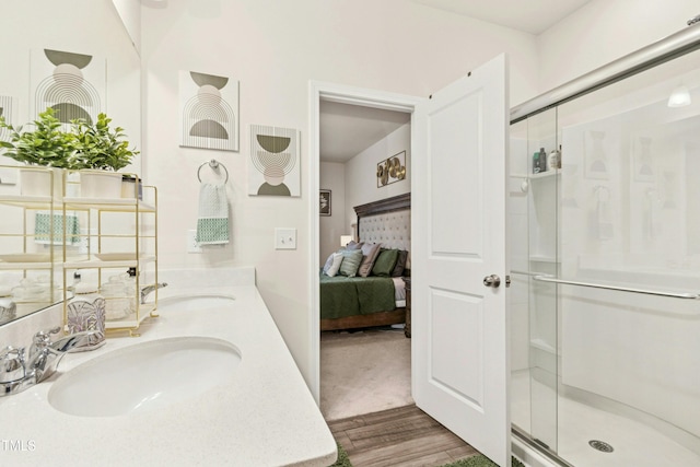 ensuite bathroom with ensuite bathroom, a shower stall, double vanity, wood finished floors, and a sink