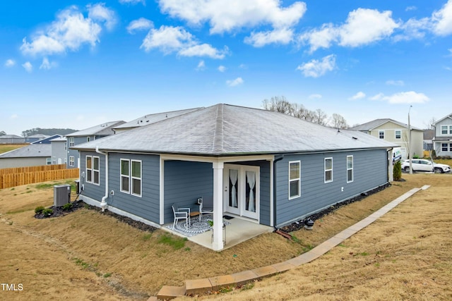 rear view of property with a shingled roof, central AC, fence, and a patio