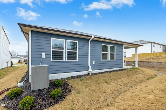 back of house with central AC unit and fence