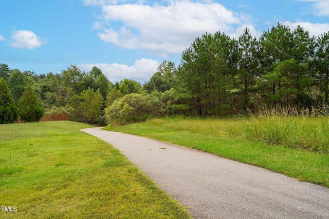 surrounding community featuring a lawn and a wooded view