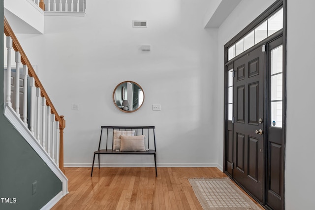 entrance foyer featuring stairway, visible vents, wood finished floors, and a healthy amount of sunlight