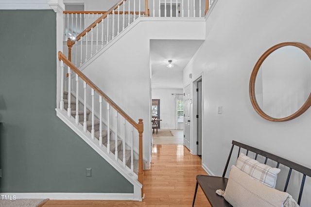 foyer featuring baseboards, wood finished floors, a high ceiling, and stairway