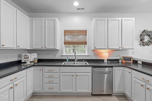 kitchen with dark countertops, visible vents, stainless steel dishwasher, and a sink